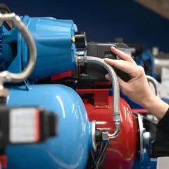 Dłoń dotyka elementu pompy hydroforowej, gdzie znajduje się presostat.