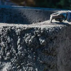 Ręka w rękawicy wygładza świeży beton B20. Sprawdzamy beton B20 cena za m3.