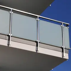 Nowoczesne mocowanie balustrady od czoła z matowego szkła i stali nierdzewnej na tle błękitnego nieba.