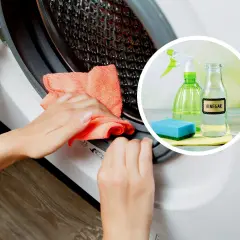 Ręce czyszczą pralkę pomarańczową ściereczką. W tle widać butelkę octu, spray i gąbkę.