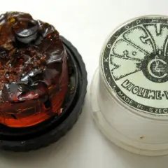 Kostka kalafonii na czarnym podkładzie obok plastikowego pudełka z napisem "VIOLINE-VIOLA MADE IN CZECHOSLOVAKIA".