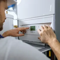 Fachowiec ustawia piec gazowy, co jest kluczowe dla kosztu instalacji gazowej w domu.