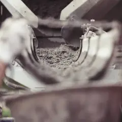 Ręka w białej rękawiczce kieruje strumień suchego cementu do maszyny. Zastanawiasz się, ile kosztuje worek cementu?