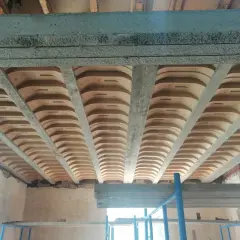 Widok od dołu na różne rodzaje stropów: betonowe belki i płyty, a także pustaki ceramiczne tworzące łuki.