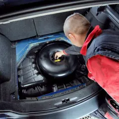 Mechanik sprawdza butlę LPG w bagażniku. Dowiedz się, ile kosztuje legalizacja butli LPG i jakie są formalności.