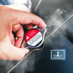 Dłoń dotyka gorącego korka chłodnicy, z którego unosi się para. Obok widoczna kontrolka płynu chłodniczego.