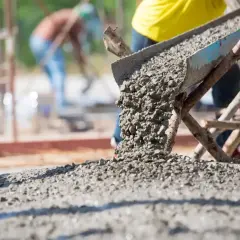 Betoniarka wylewa świeży beton. Pracownicy na budowie dbają o odpowiednią ilość cementu na kubik betonu, by zapewnić trwałość konstrukcji.