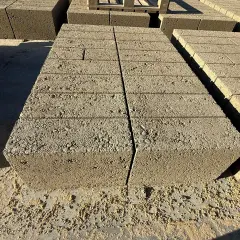 Stosy betonowych pustaków, każdy o standardowych bloczek betonowy wymiary, czekają na budowę.