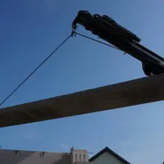 Dźwig podnosi betonowy strop nad budowę.