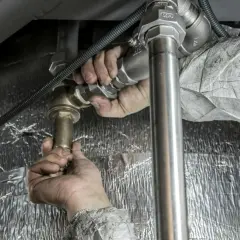Ręce hydraulika montują baterię podtynkową. Sprawdź montaż baterii podtynkowej cena.