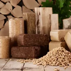 Różne rodzaje brykietu i pelletu drzewnego na drewnianym tle.