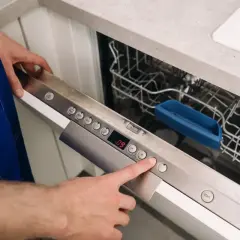Ręka naciska przycisk na panelu zmywarki Whirlpool, pokazując, jak zresetować zmywarkę Whirlpool.