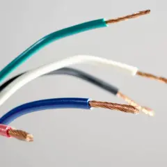 Pięć przewodów elektrycznych w różnych kolorach: zielonym, białym, czarnym, niebieskim i różowym, odsłaniających miedziane żyły. Różnorodność kolorów faz ułatwia identyfikację.