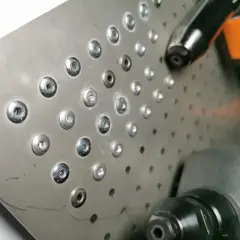 Metalowa blacha z rzędem nitów zrywanych i narzędziem do ich montażu.