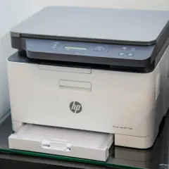 Biała drukarka HP z panelem sterowania i wysuniętą szufladą na papier. Idealna do domu, bo to drukarka tania w eksploatacji.