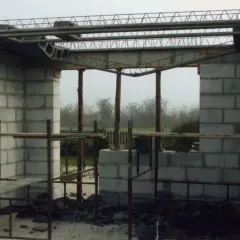 Budowa domu w toku. Widać betonowe pustaki, rusztowania i elementy stropu żelbetowego.