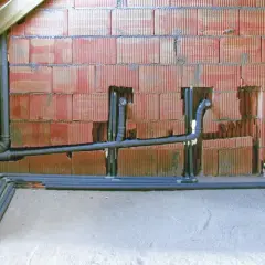 Instalacja kanalizacyjna w trakcie budowy, widoczne rury i podejścia, przygotowanie do odpowietrzenia kanalizacji.