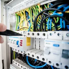 Elektryk sprawdza bezpieczniki w rozdzielni. Może to być związane z problemem: brak jednej fazy w domu.
