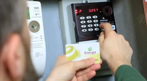 Doładowanie licznika przedpłatowego Energa. Osoba wprowadza kod na klawiaturze urządzenia.