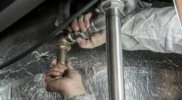Ręce hydraulika montują baterię podtynkową. Sprawdź montaż baterii podtynkowej cena.