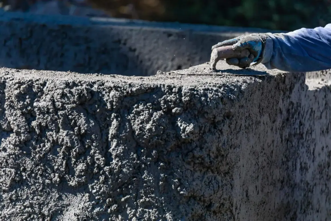 Ręka w rękawicy wygładza świeży beton B20. Sprawdzamy beton B20 cena za m3.