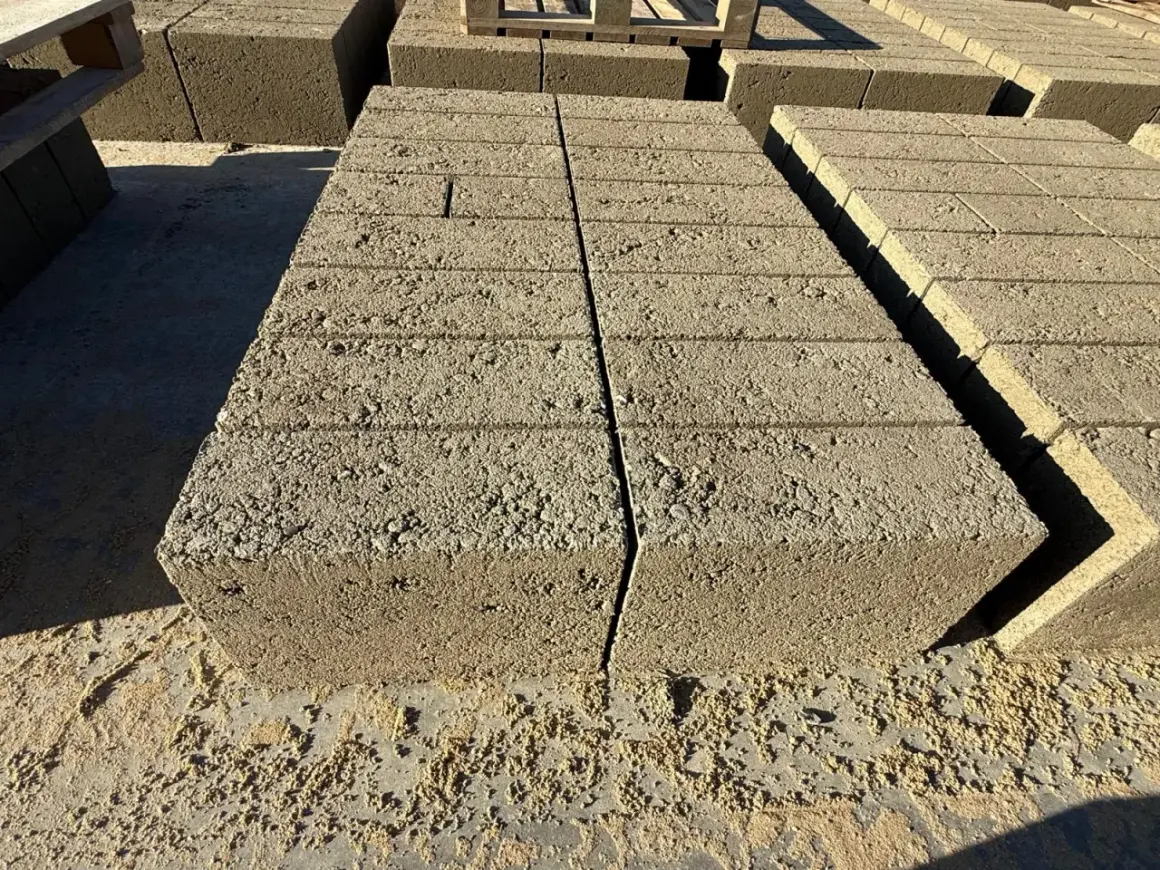 Stosy betonowych pustaków, każdy o standardowych bloczek betonowy wymiary, czekają na budowę.