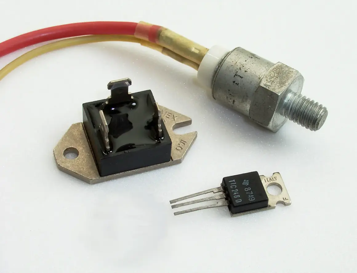 Trzy elementy elektroniczne: mostek prostowniczy, tranzystor TIC246D i metalowy element z gwintem, prawdopodobnie regulator napięcia.
