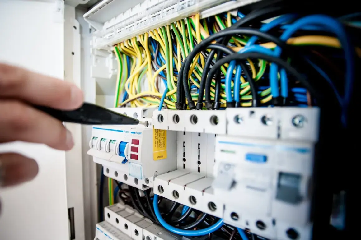 Elektryk sprawdza bezpieczniki w rozdzielni. Może to być związane z problemem: brak jednej fazy w domu.