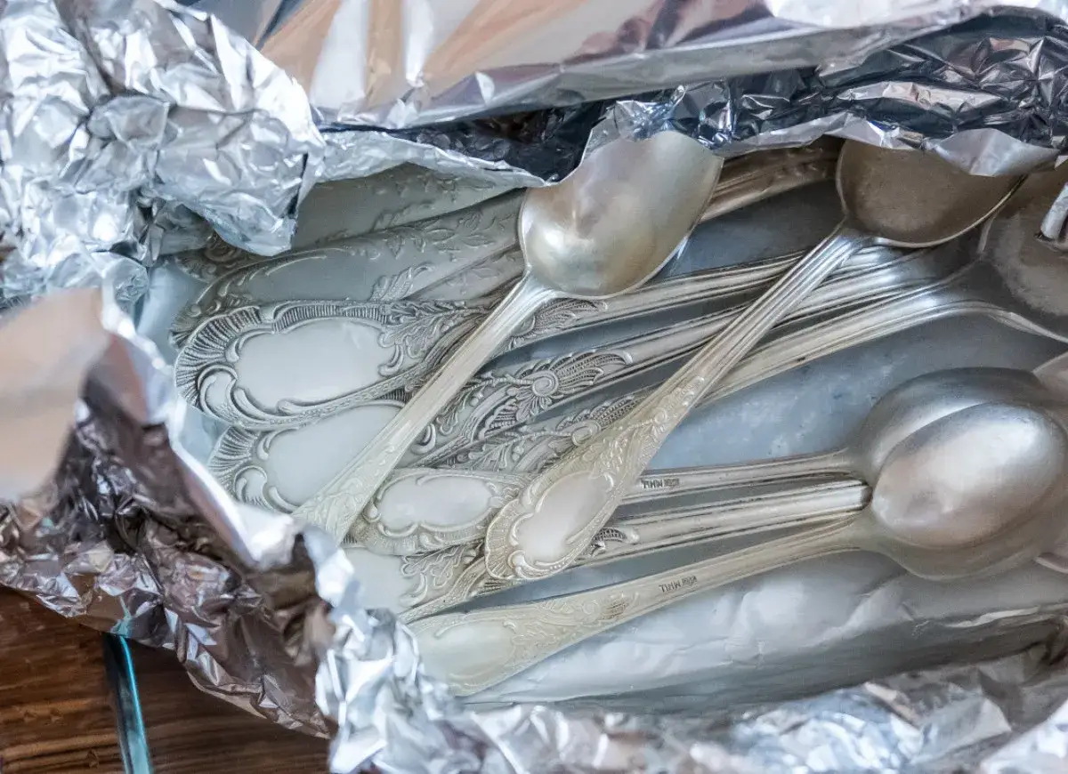Stare, ozdobne łyżki w folii aluminiowej, gotowe do czyszczenia. Dowiedz się, jak wyczyścić srebro, by odzyskało blask.