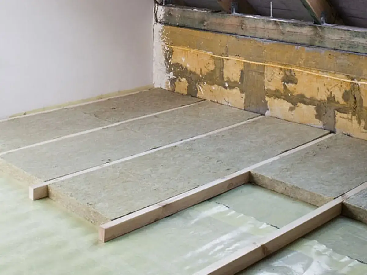 Ocieplenie stropu betonowego na poddaszu nieużytkowym: wełna mineralna ułożona na folii, pod legarami.