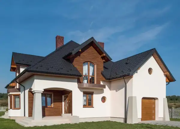 Nowoczesny dom z drewnianymi elementami i białym tynkiem. Solidny cokół na elewacji chroni budynek.