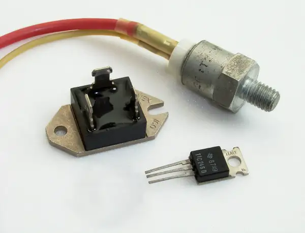Trzy elementy elektroniczne: mostek prostowniczy, tranzystor TIC246D i metalowy element z gwintem, prawdopodobnie regulator napięcia.